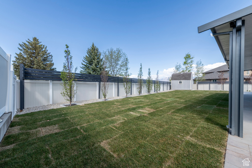 View of yard featuring an outdoor structure, a fenced backyard, and a storage unit