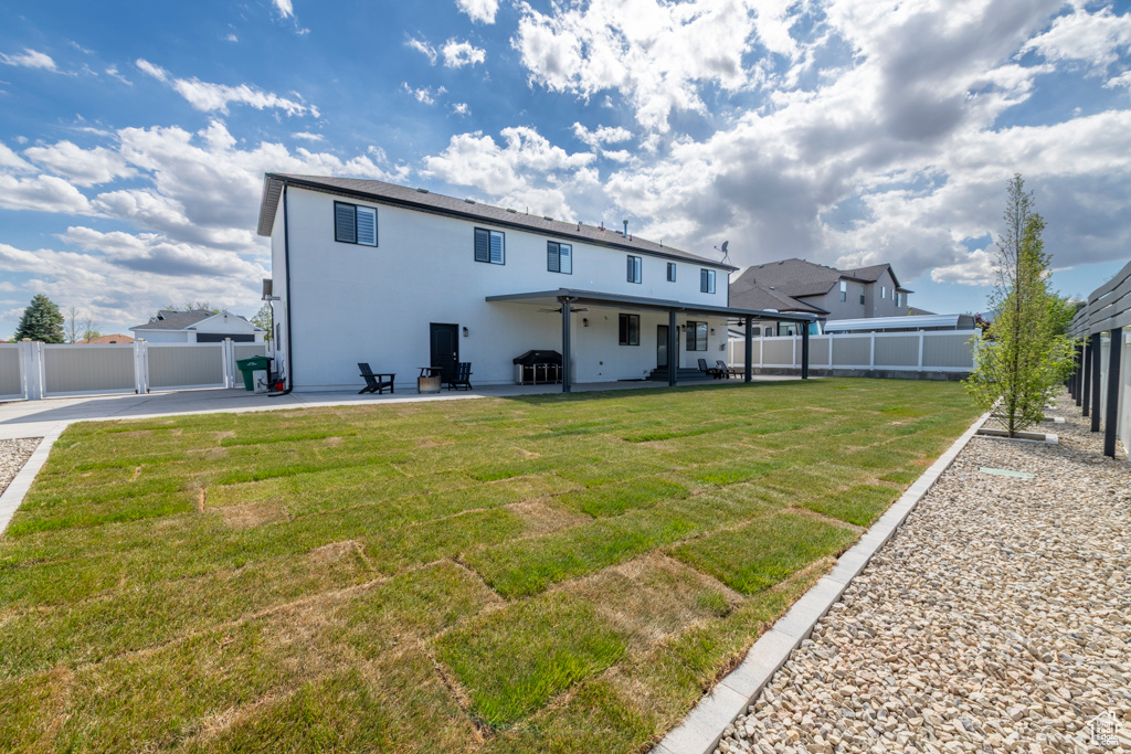 Back of property with a patio, a fenced backyard, a ceiling fan, and a yard