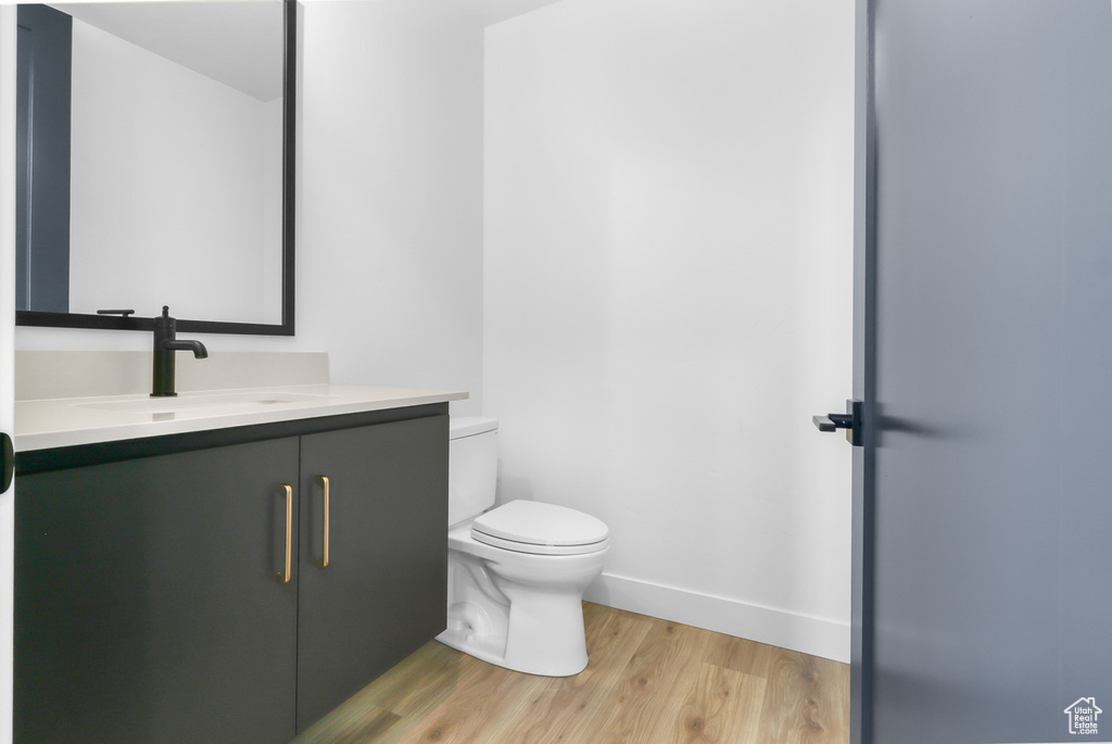 Bathroom with toilet, wood finished floors, vanity, and baseboards