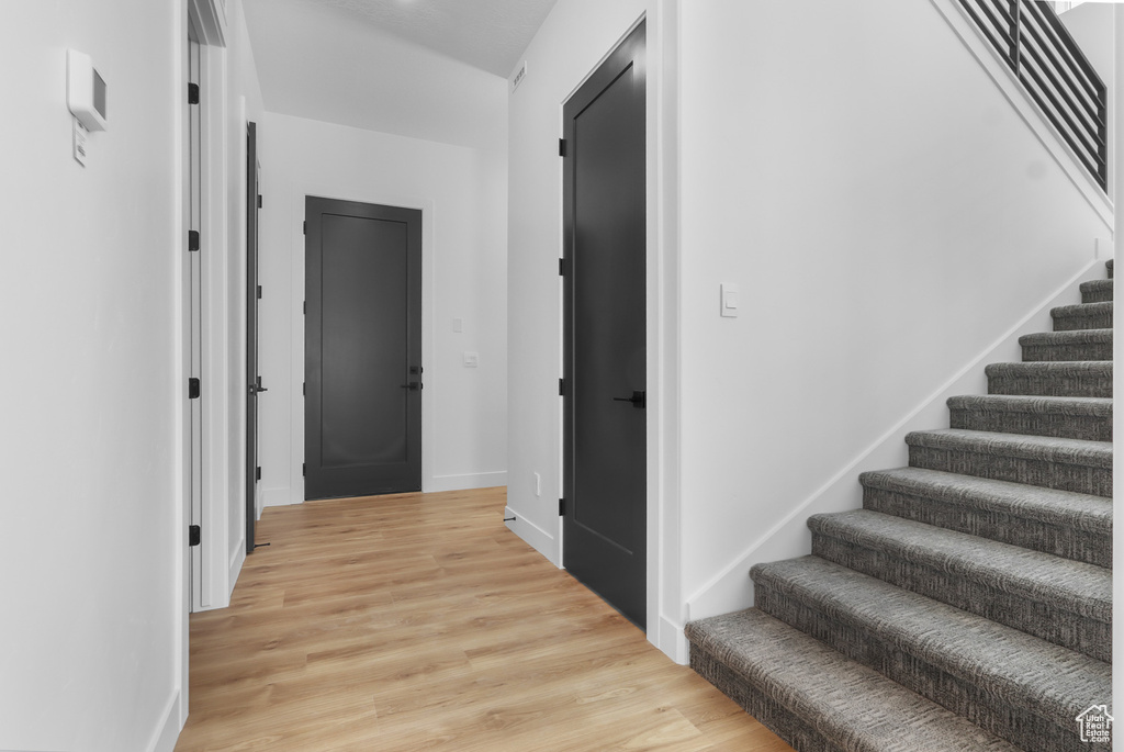 Hallway with stairway, light wood-style flooring, and baseboards