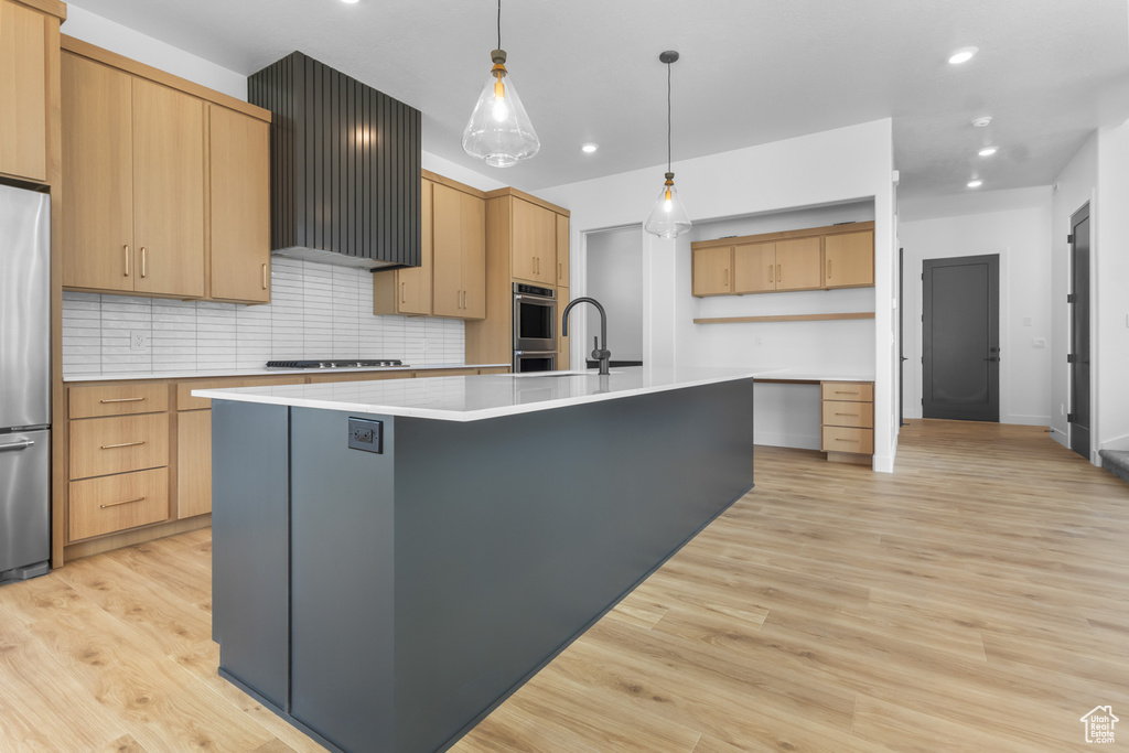 Kitchen with an island with sink, decorative backsplash, light countertops, recessed lighting, and stainless steel appliances