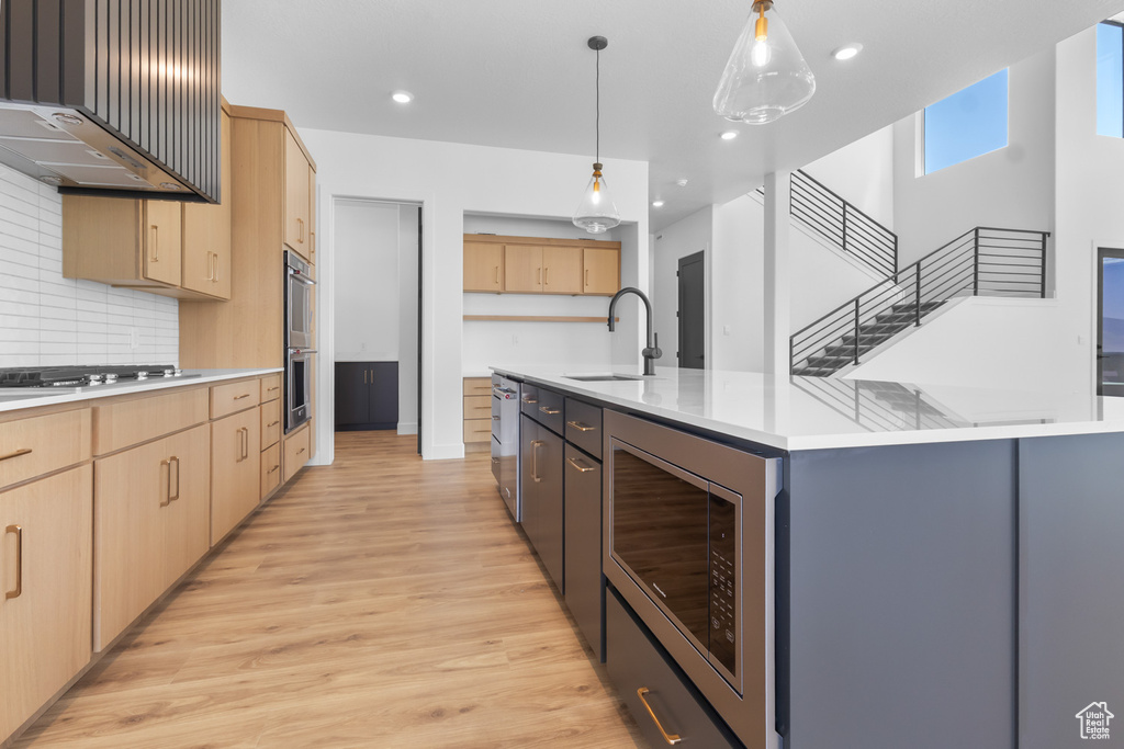 Kitchen featuring a sink, light brown cabinets, stainless steel appliances, light wood-style flooring, and light countertops