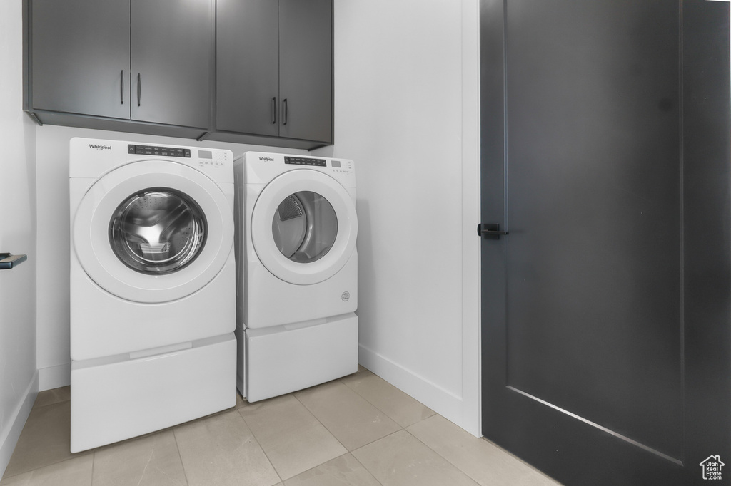 Laundry area with cabinet space, washer and clothes dryer, baseboards, and light tile patterned floors