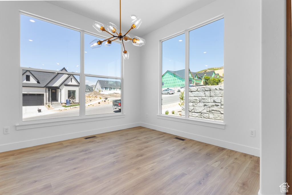 Unfurnished room with a chandelier, baseboards, and wood finished floors