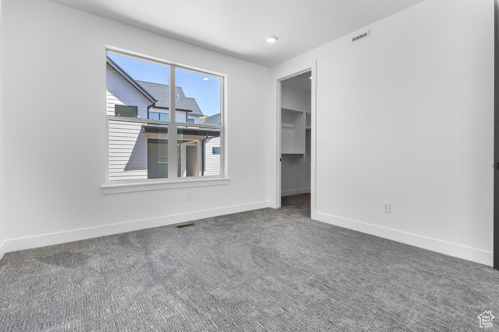 Unfurnished bedroom with baseboards, a walk in closet, and carpet flooring