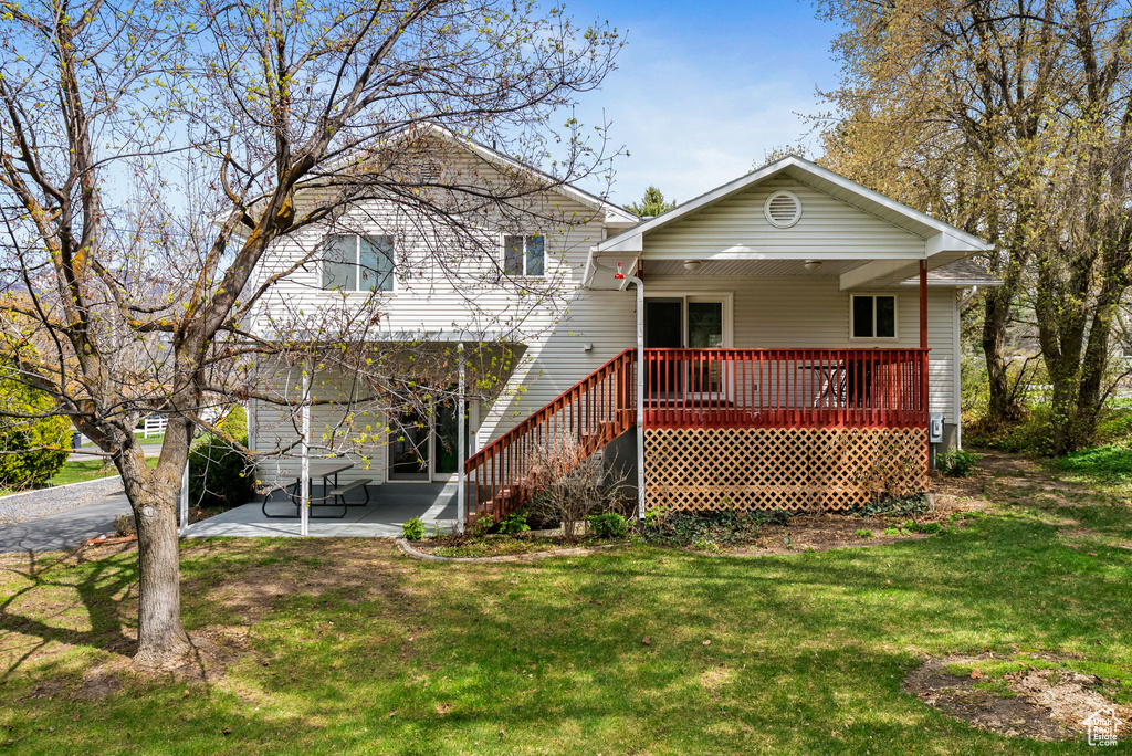 Back of house featuring a lawn, covered porch, and a patio