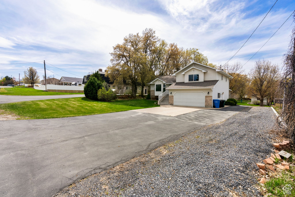 View of front of property with an attached garage, driveway, brick siding, and a front yard