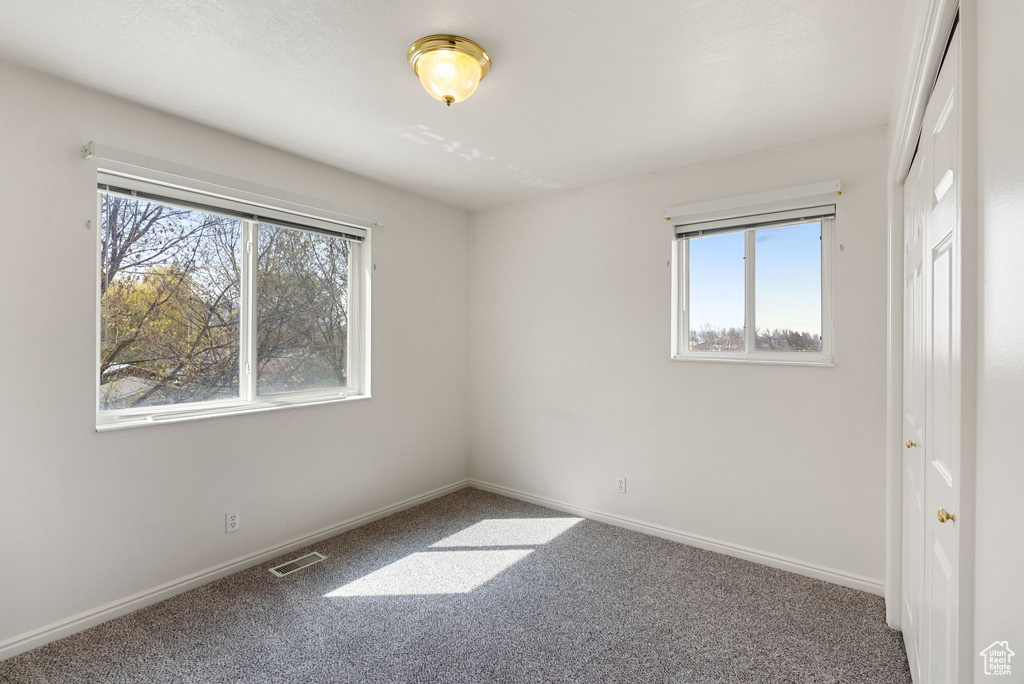 Carpeted empty room with baseboards and visible vents