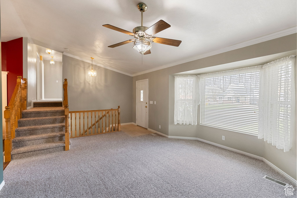 Empty room featuring visible vents, a ceiling fan, carpet floors, crown molding, and baseboards