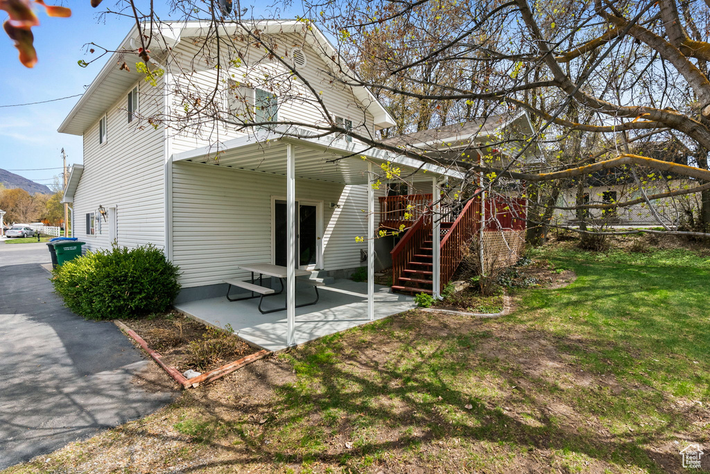 Back of house with a lawn, stairway, and a patio area