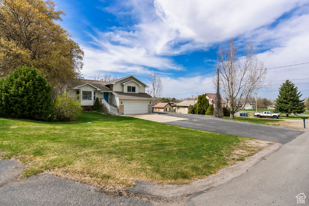 View of front facade featuring a front lawn, driveway, a garage, brick siding, and a shingled roof