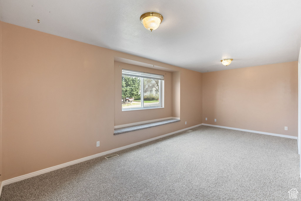 Carpeted empty room featuring visible vents and baseboards