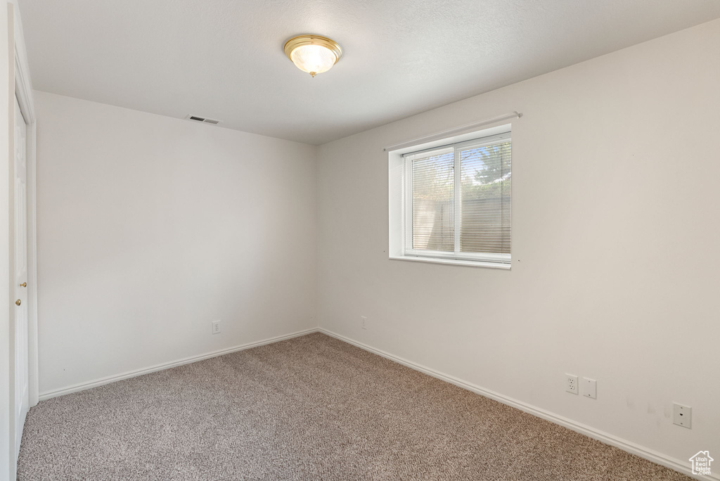 Carpeted empty room with visible vents and baseboards