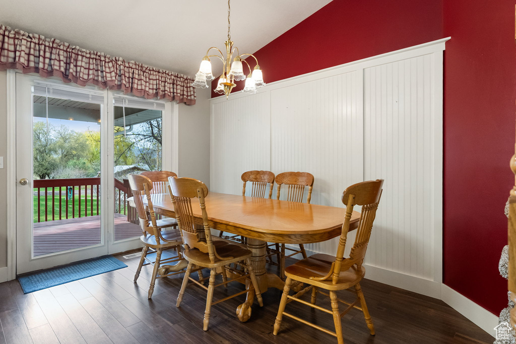 Dining area featuring dark wood finished floors, lofted ceiling, a notable chandelier, and baseboards