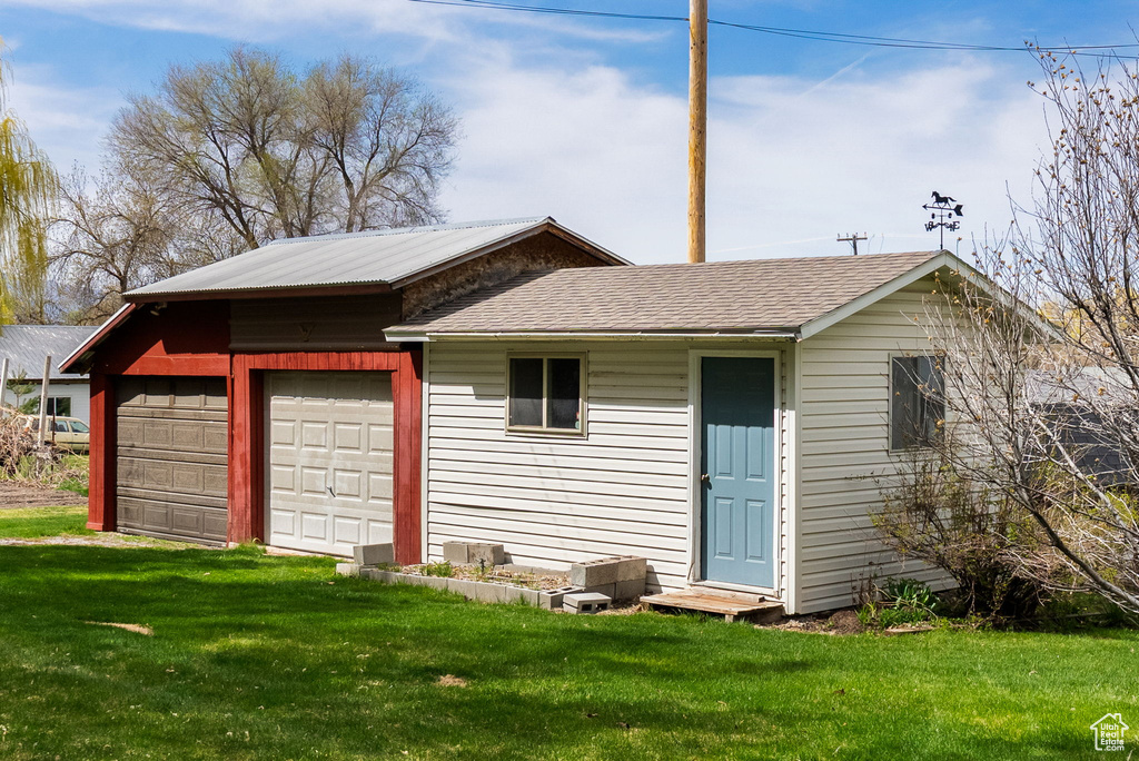 Exterior space with a lawn, a shingled roof, and a garage