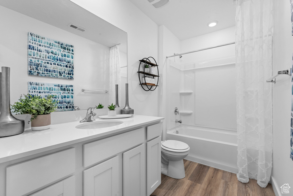Full bath with shower / tub combo, vanity, toilet, visible vents, and wood finished floors