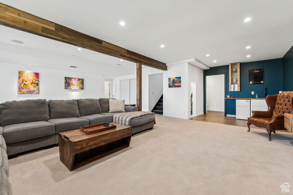 Living room featuring indoor bar, beam ceiling, recessed lighting, stairway, and light carpet