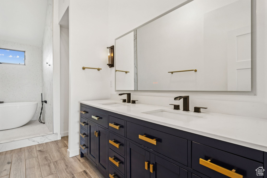 Bathroom with a freestanding tub, double vanity, a sink, and wood finished floors