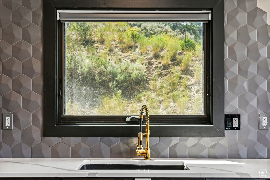 Room details featuring light stone countertops, a sink, and decorative backsplash