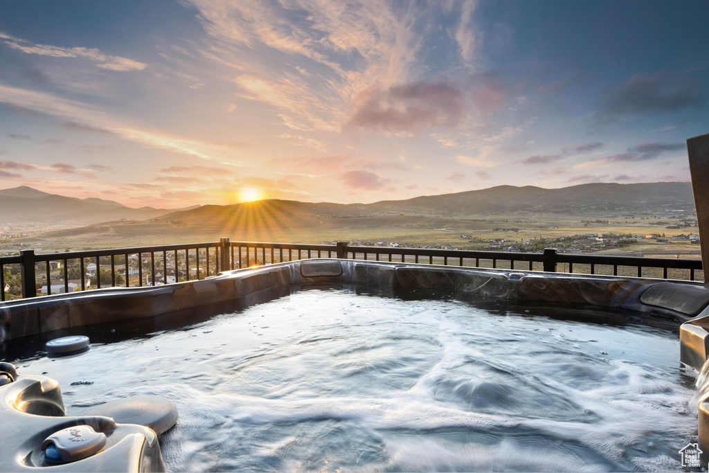 Deck at dusk with a mountain view and a hot tub