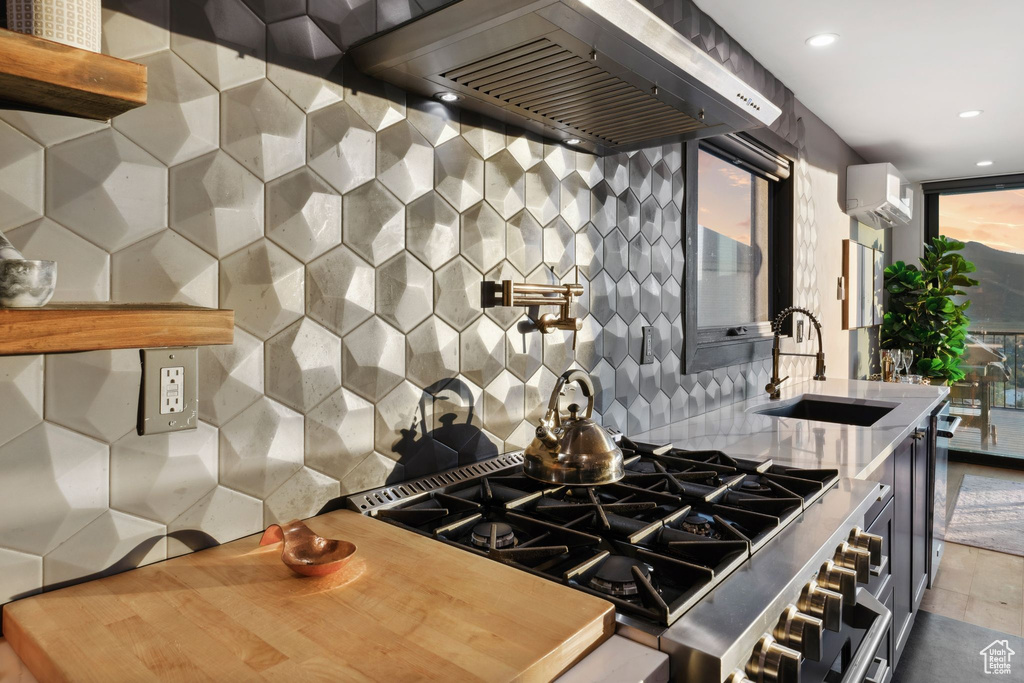 Kitchen featuring recessed lighting, wall chimney exhaust hood, a wall unit AC, decorative backsplash, and a sink