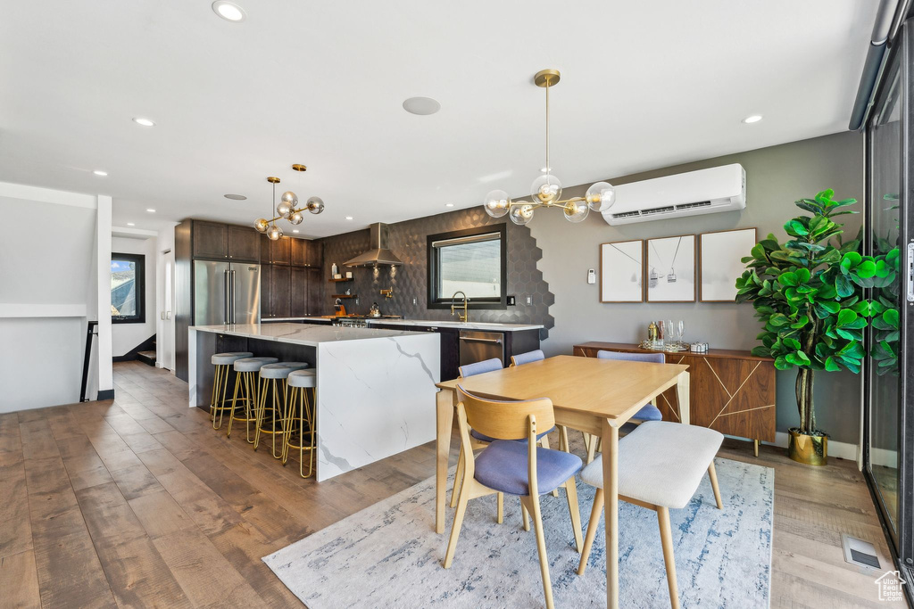 Dining space with visible vents, a notable chandelier, light wood-style floors, recessed lighting, and a wall unit AC