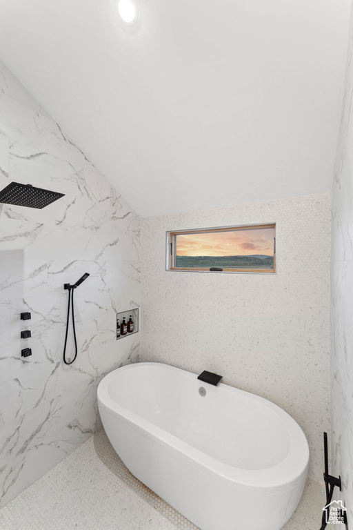 Bathroom with a freestanding tub, a marble finish shower, and tile walls