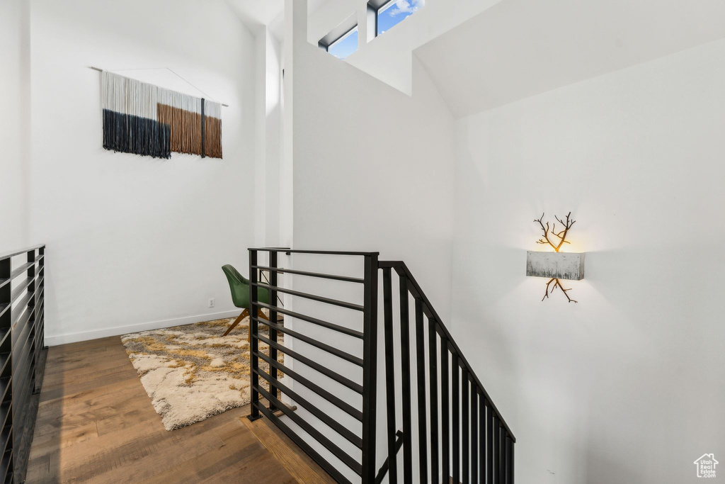 Stairs with wood finished floors, high vaulted ceiling, and baseboards
