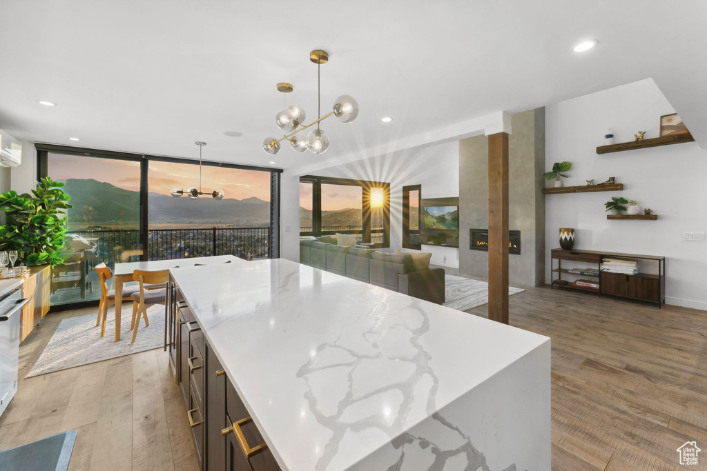 Kitchen featuring light wood-style floors, pendant lighting, recessed lighting, a chandelier, and light stone counters