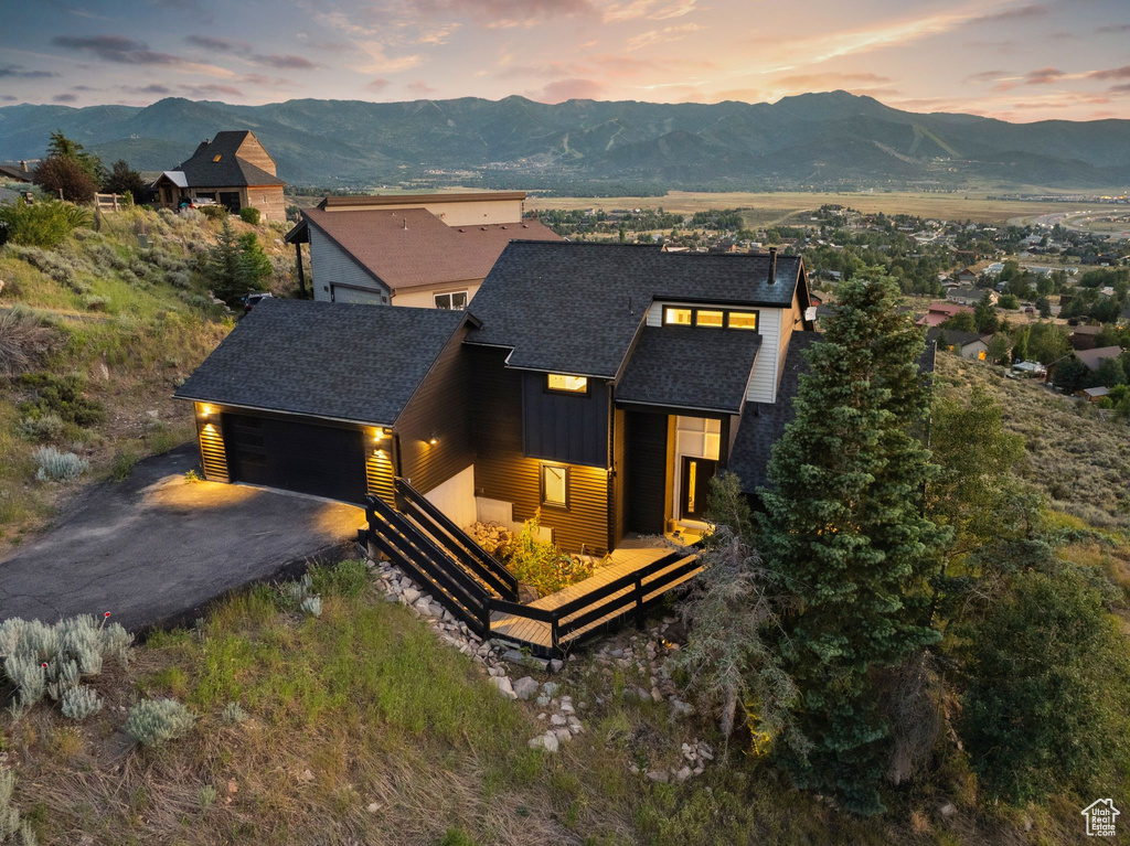 Modern home featuring board and batten siding, aphalt driveway, a mountain view, an attached garage, and a shingled roof
