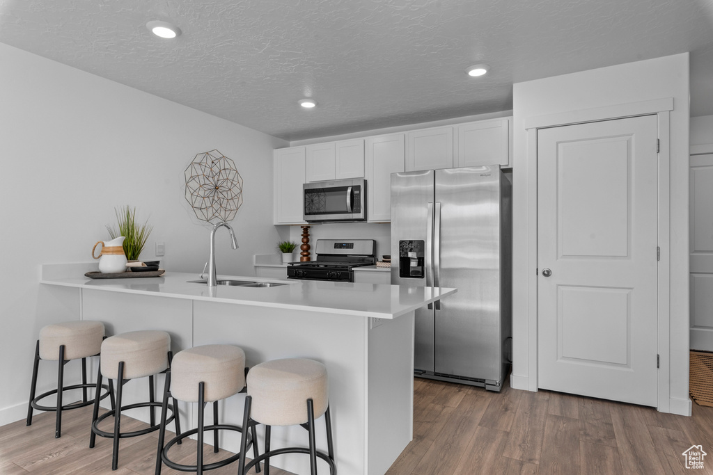 Kitchen with a sink, light wood-type flooring, a peninsula, stainless steel appliances, and a breakfast bar area