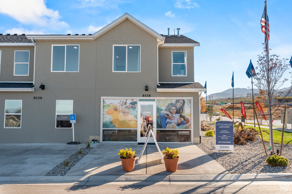 Exterior space featuring roof with shingles, a mountain view, and stucco siding