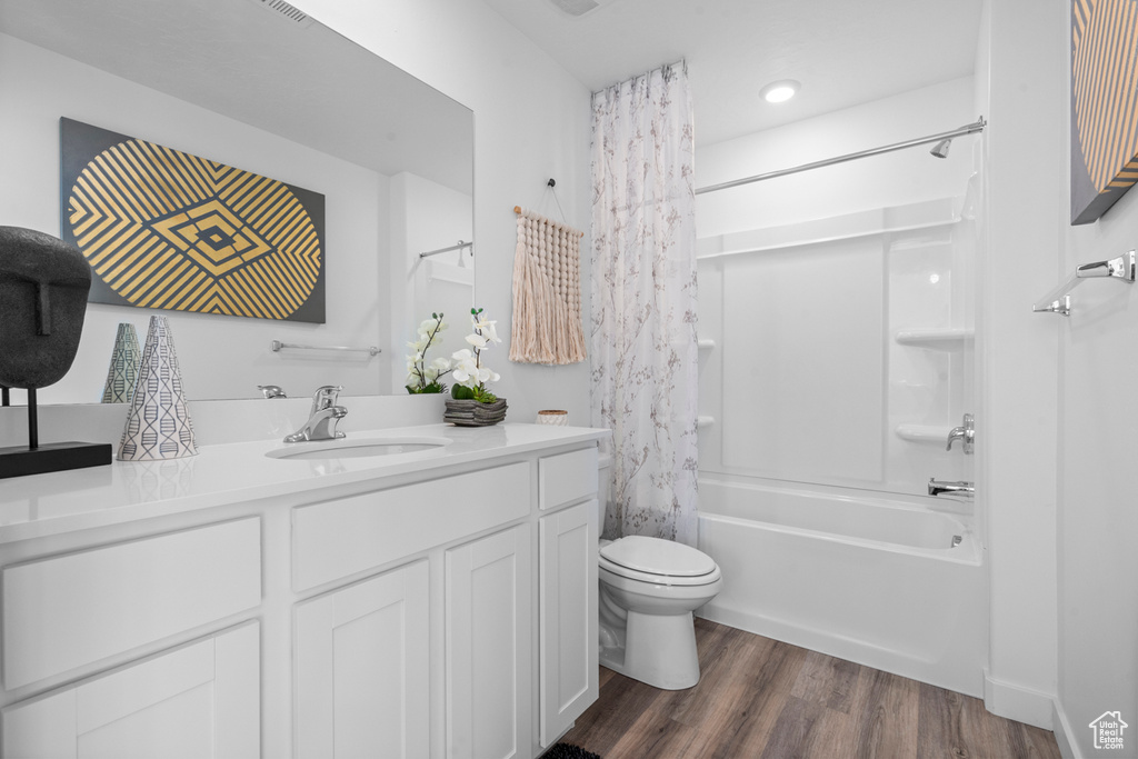 Full bath with shower / tub combo, toilet, recessed lighting, vanity, and wood finished floors