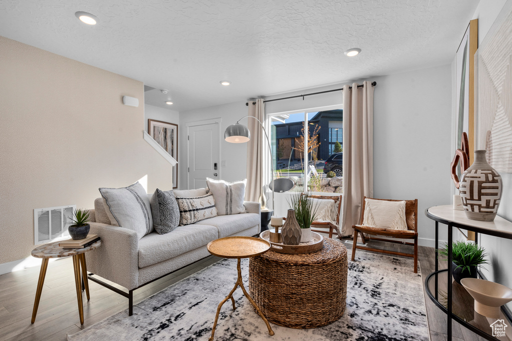 Living area with visible vents, stairway, recessed lighting, wood finished floors, and baseboards