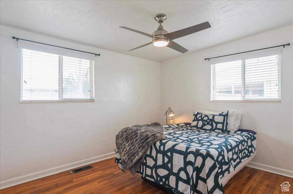 Bedroom with wood finished floors, baseboards, and multiple windows