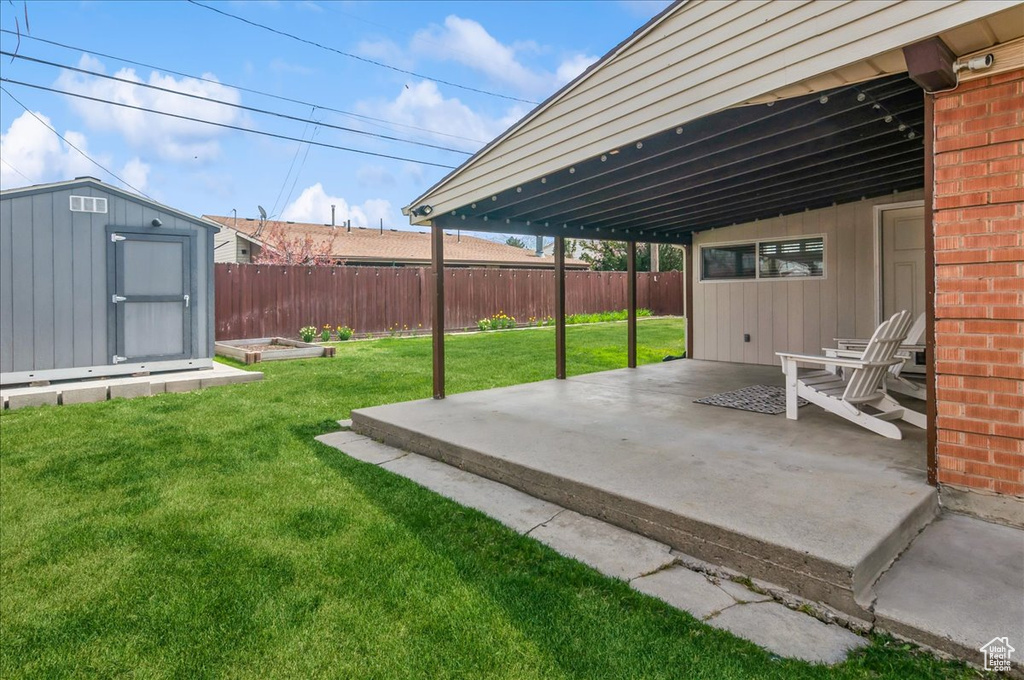 View of yard with a patio, an outbuilding, a storage unit, and fence