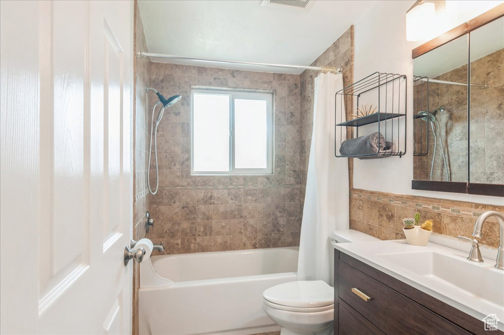 Full bath with visible vents, toilet, vanity, and shower / bath combination with curtain