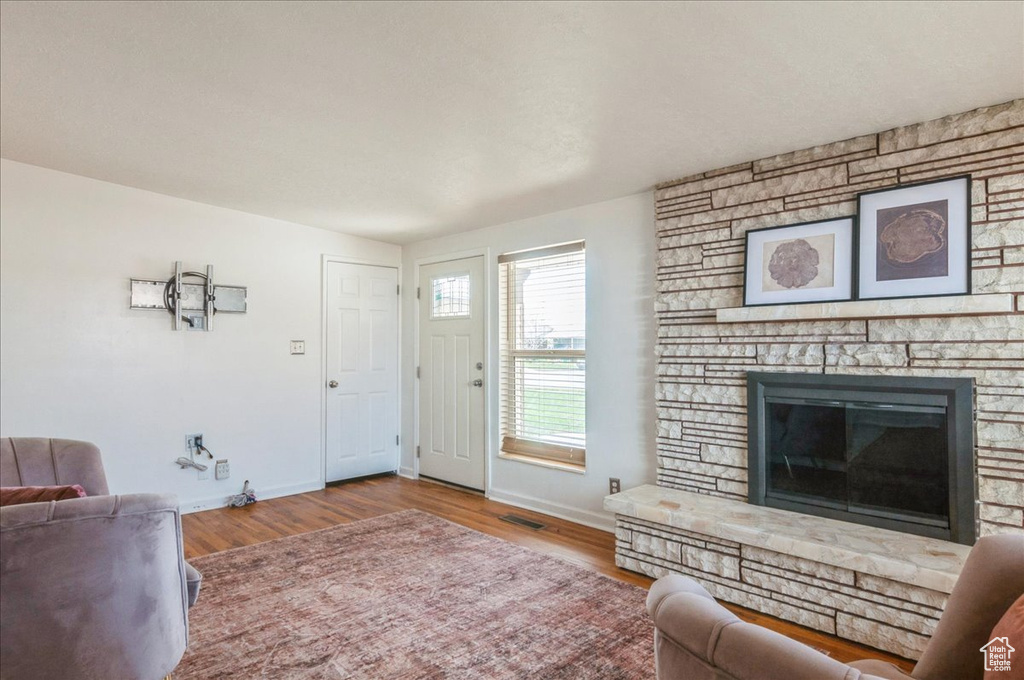 Living area with wood finished floors, a fireplace, baseboards, and visible vents
