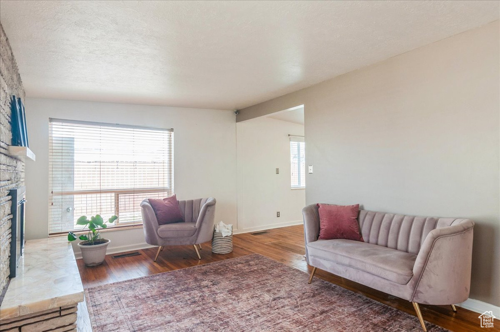 Sitting room featuring a stone fireplace, baseboards, and wood finished floors