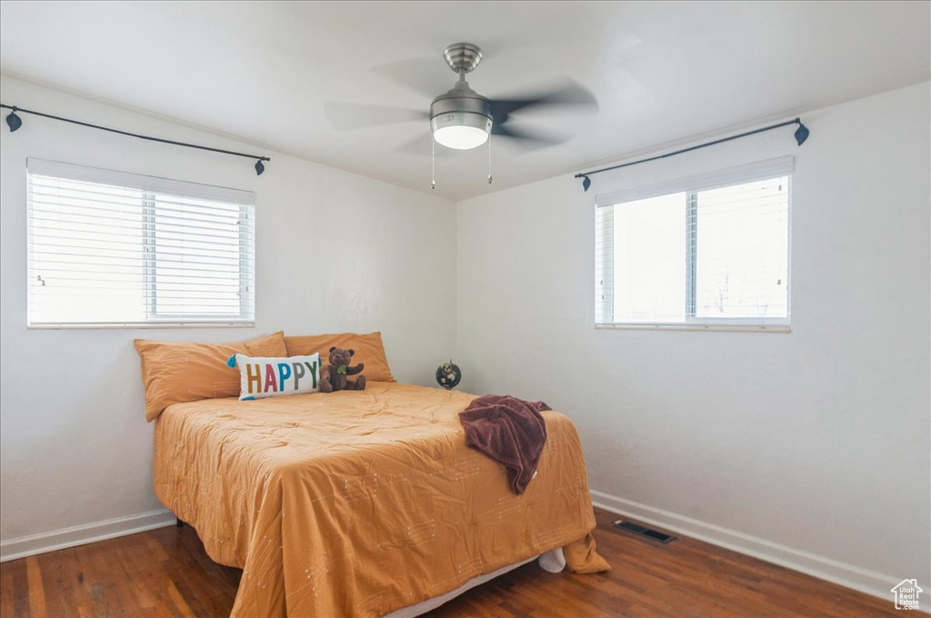 Bedroom with dark wood-style flooring, visible vents, baseboards, and multiple windows
