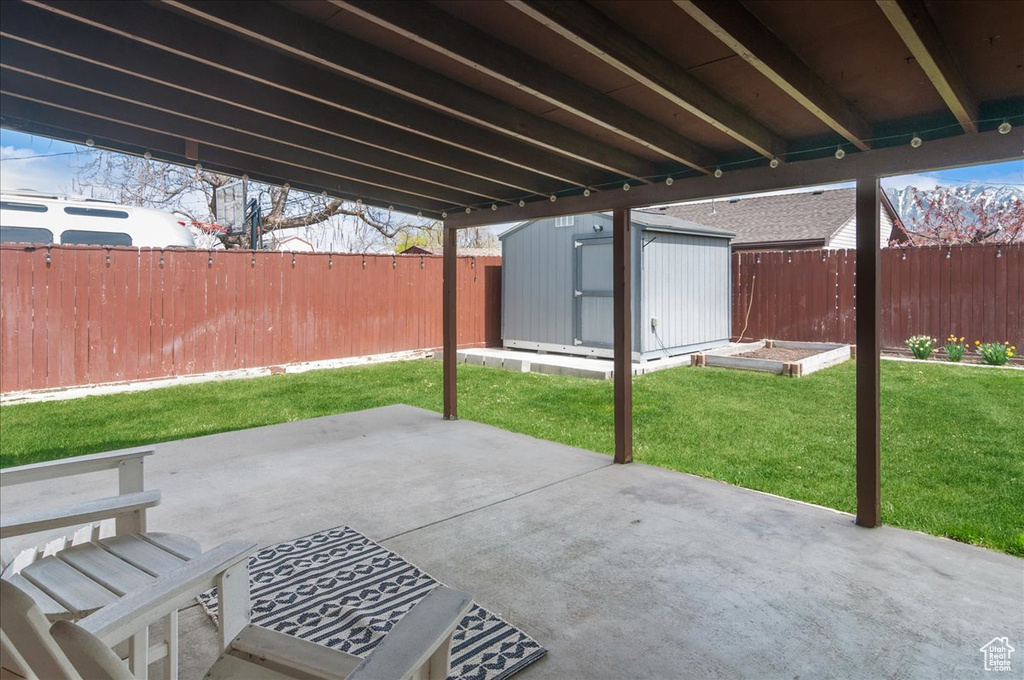 View of patio / terrace with a storage shed, a fenced backyard, a vegetable garden, and an outdoor structure