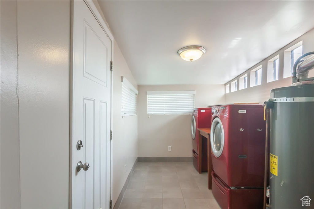 Washroom with washer and dryer, laundry area, baseboards, and water heater