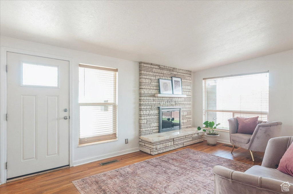 Living room featuring a fireplace, visible vents, baseboards, and wood finished floors