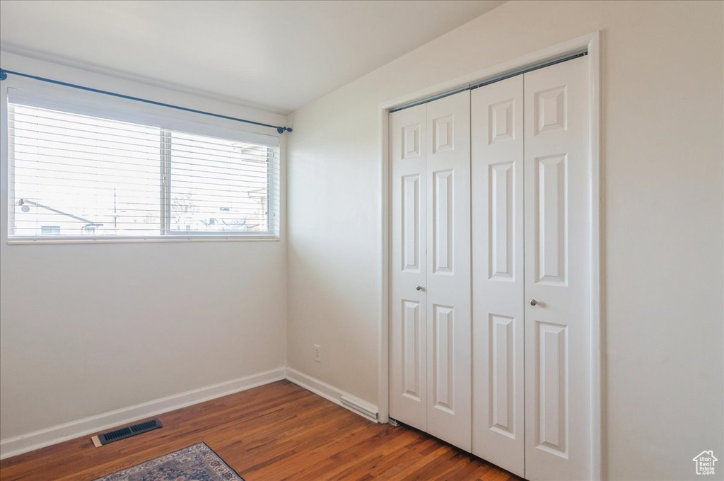 Unfurnished bedroom with visible vents, a closet, baseboards, and wood finished floors