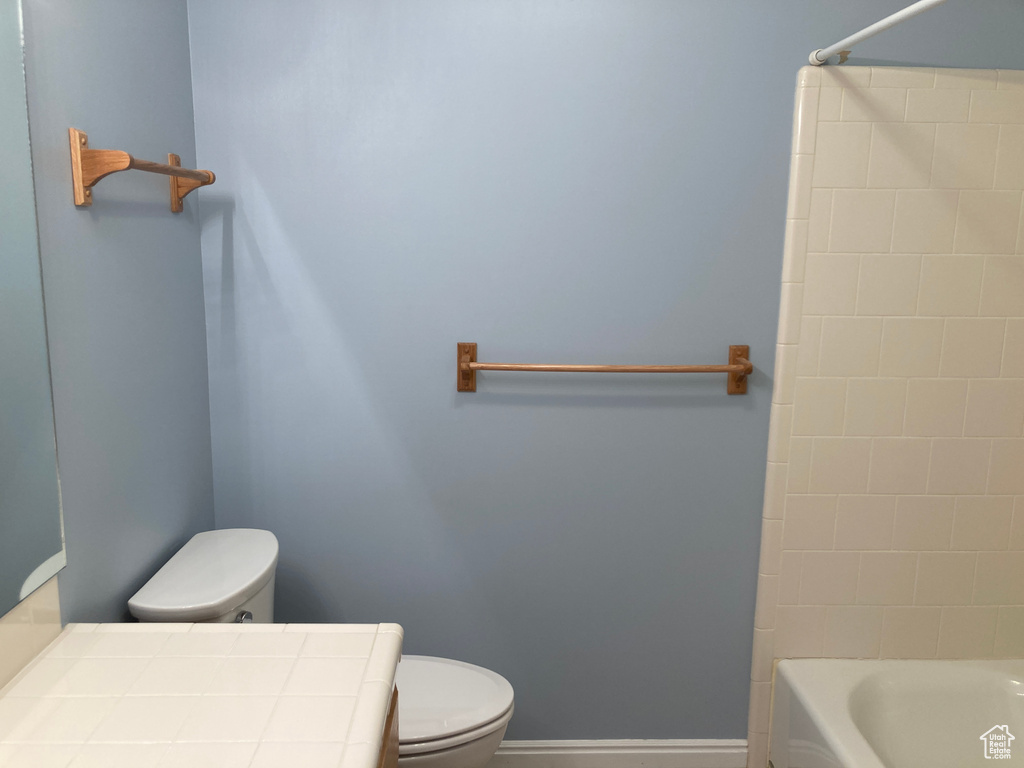 Full bathroom featuring toilet, shower / bath combination, and baseboards