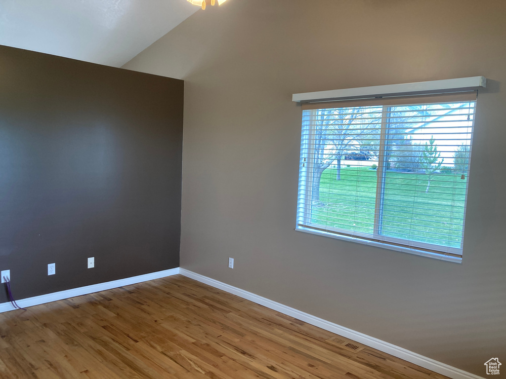Spare room featuring a wealth of natural light, baseboards, and wood finished floors