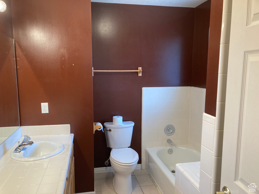 Full bath featuring vanity, baseboards, tile patterned flooring, toilet, and a bath