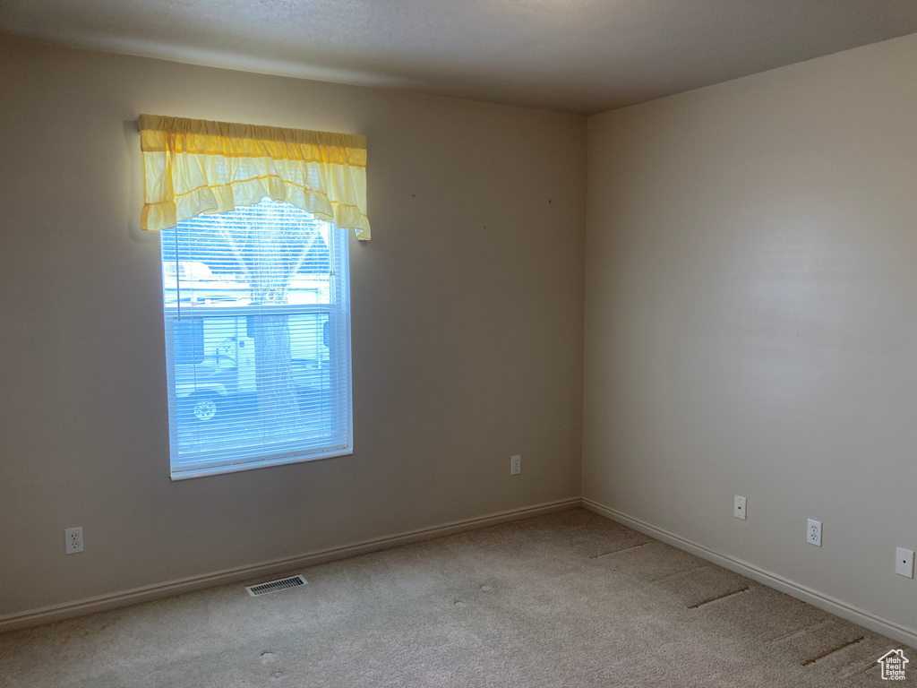 Empty room featuring carpet flooring, baseboards, and visible vents