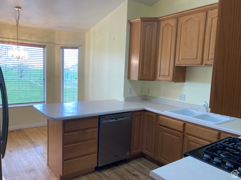 Kitchen featuring a notable chandelier, light wood-type flooring, a peninsula, dishwasher, and a sink