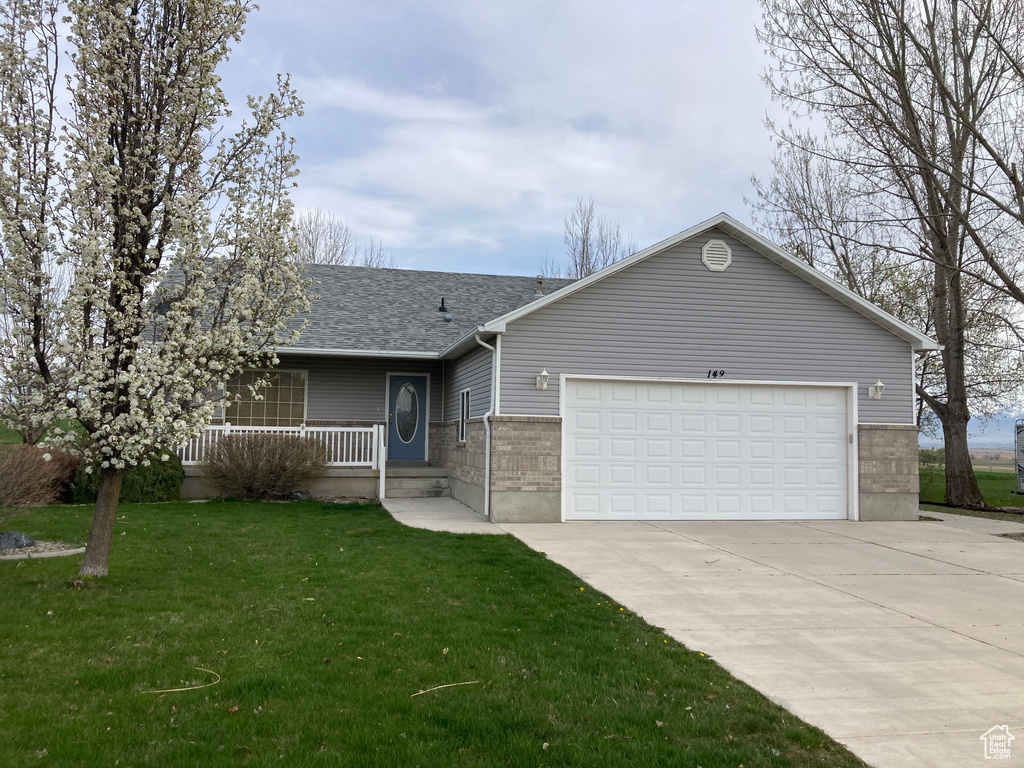 Ranch-style house with an attached garage, covered porch, a front lawn, driveway, and roof with shingles